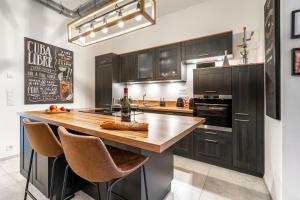 a kitchen with black cabinets and a wooden island with bar stools at Beautiful Design 2 BR Loft in Mertert