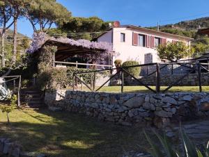 a house with a stone fence and a stone wall at Sea view villa with large garden in Campo nell'Elba