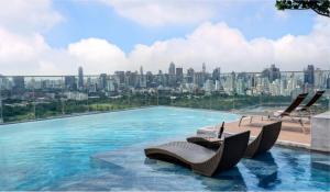 a swimming pool with chairs and a city skyline at Wyndham Bangkok Queen Convention Centre in Bangkok