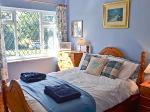 a bedroom with a bed with blue walls and a window at Isabella Cottage in Heddon on the Wall