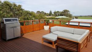 a patio with a couch and a grill on a deck at SeymourViews Apollo Bay in Apollo Bay