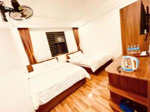 a bedroom with two beds and a desk and a mirror at Thanh Phương Hotel 2 Hà Giang in Mèo Vạc