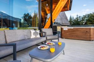 a patio with a couch and a table with drinks on it at Tatra Heaven Residence & Jacuzzi in Kościelisko