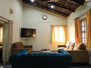 a living room with two couches and a clock on the wall at Mannath lands end Beach house in Kaup