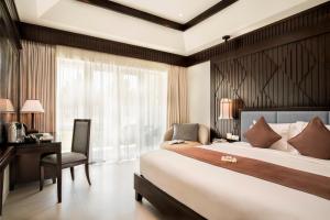 a bedroom with a large bed and a desk and a chair at Boutique Hoi An Resort in Hoi An +58 photos