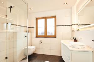 a white bathroom with a toilet and a sink at Krennlehen in Schönau am Königssee +31 photos