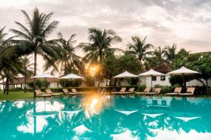 a pool at a resort with chairs and umbrellas at Boutique Hoi An Resort in Hoi An