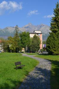 een bankje in een park met bergen op de achtergrond bij Apartmán Leny in Tatranská Lomnica