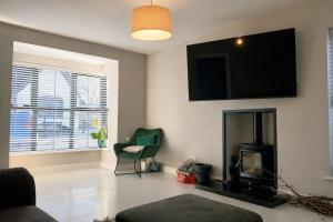 a living room with a fireplace and a flat screen tv at Private room in shared house at Casa de Charlie in Lambeg +5 photos