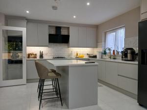 a kitchen with white cabinets and a bar with a stool at Private room in shared house at Casa de Charlie in Lambeg