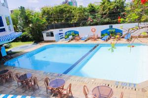 a large swimming pool with chairs and tables at The Initial Residence in Mombasa