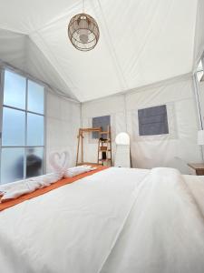 a white bedroom with a large bed and a window at Ohara Glamping in Kubupenlokan +18 photos