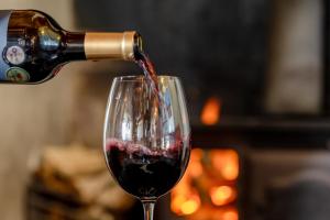 a person pouring red wine into a wine glass at The Farmhouse Hotel in Langebaan