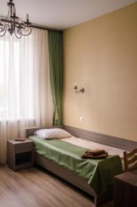 a bedroom with a bed with green sheets and a window at Apart-Hotel Camelot in Pskov