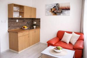 a living room with a red couch and a kitchen at Dusan Apartments in Orlová