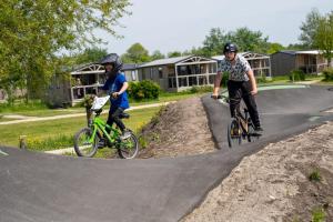 two people riding bikes on a skateboard ramp at Stacaravan 161 Capfun camping Bongerd 5 sterren Gezin 5 personen in Tuitjenhorn