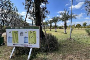 a sign in a park with palm trees in the background at Honey Queen Resort in Ban Tha Manao