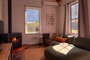 a living room with a couch and a fireplace at Clonmara Country House and Cottages in Port Fairy