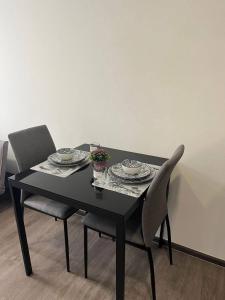 a black table with two chairs and plates and flowers on it at The8collaction in Bangkok