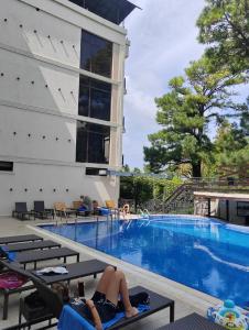 a person laying on chairs next to a swimming pool at Hotel AnOrita in Kobuleti +183 photos