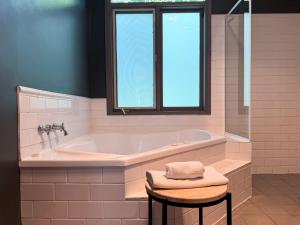 a bathroom with a tub and a window and a stool at Clonmara Country House and Cottages in Port Fairy
