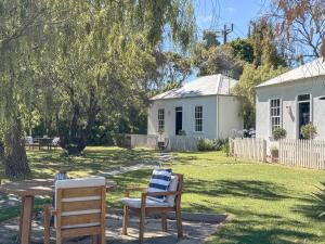 a house with two chairs and a table in a yard at Clonmara Country House and Cottages in Port Fairy