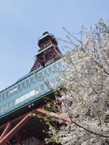 a tower withakuraakura trees in front of a building at シティスカイコート - 清潔で快適 家具や設備充実の快適ステイ in Sapporo