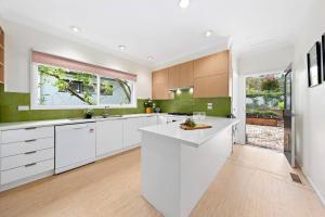 a kitchen with white cabinets and a large window at Elegant 4BR Sanctuary with Private Pool in Warrawee