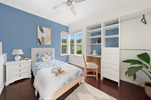 a bedroom with blue walls and a bed with a desk at Elegant 4BR Sanctuary with Private Pool in Warrawee