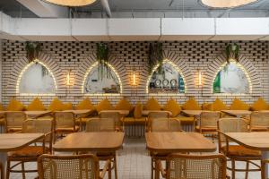 a dining room with tables and chairs and a brick wall at IGMAR Villas & Aparts Hotel in Tashkent