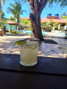 a drink sitting on top of a table with a palm tree at Pousada do Sol in Aquiraz