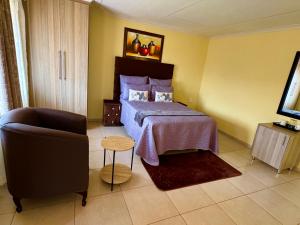 a bedroom with a bed and a chair and a television at BotseBontle Lodge in Lenting