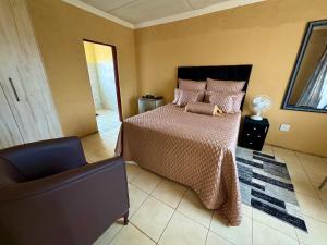 a bedroom with a bed and a chair at BotseBontle Lodge in Lenting +11 photos