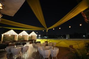 a group of chairs and tables on a patio at night at Frolic Hotel Near Sec 52 Noida Metro Station in Noida