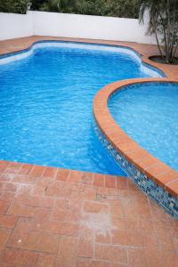 a swimming pool with a brick border and blue water at Vaidosa Guesthouse in Maputo
