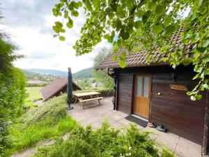 a wooden cabin with a picnic table in front of it at Chalet 6 pers près du lac de Longemer et des pistes in Xonrupt-Longemer