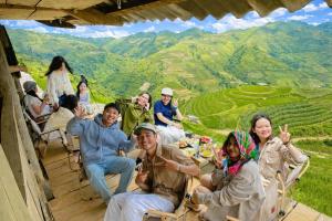 a group of people sitting around a table with a view at Xìu Homestay Tà Xùa in Bắc Yên