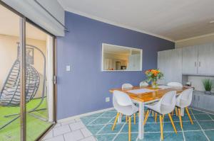a dining room with a wooden table and white chairs at Flip-Flop Flat in Langebaan +3 photos