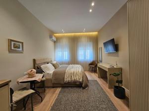 a bedroom with a bed and a desk and a television at Rroji Urban Heritage - Boutique Rooms & Serviced Apartments in City Center in Shkodër