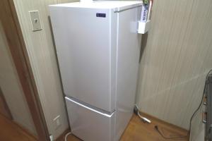 a white refrigerator in a corner of a room at 釣り宿yasakabase guesthouse in Sado