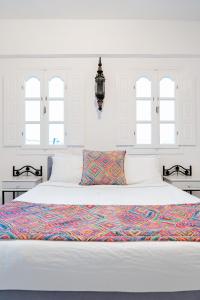 a white bedroom with a large white bed with windows at Salvatore Caldera Suites in Imerovigli +92 photos