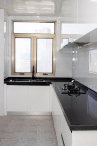 a white kitchen with black counter tops and windows at A One Oasis River View Hotel in Phnom Penh