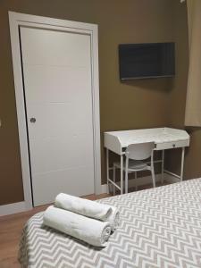 a bedroom with a bed and a desk with towels at Hostal DS in Velilla de San Antonio