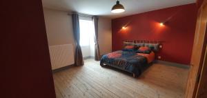 a bedroom with a bed and a red wall at La Tanière in Sirod