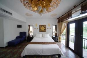 a bedroom with a large bed and a blue couch at Pludhaya Resort & Spa in Phra Nakhon Si Ayutthaya