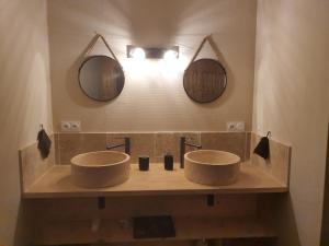 a bathroom with two sinks and two mirrors at La Tanière in Sirod