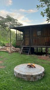 a building with a fire pit in the grass at Glocke Mountain Camp, Cabin in Outjo