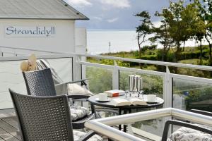 Un balcón con sillas y una mesa con tazas y vistas. en Ferienwohnung Oberdeck, en Juliusruh