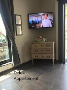 a television on a wall with a dresser in a room at Apartlogie in Tongeren