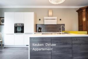 a kitchen with white cabinets and a kitchen island at Apartlogie in Tongeren